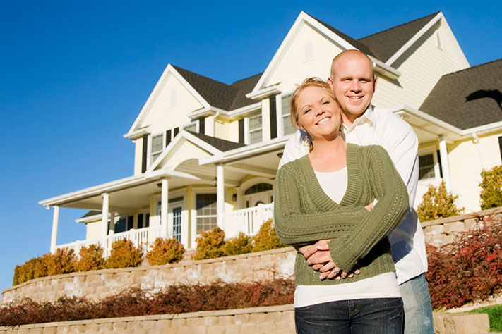 Young couple embraced in front of home with porch